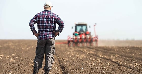 young farmer on farmland with tractor in background
